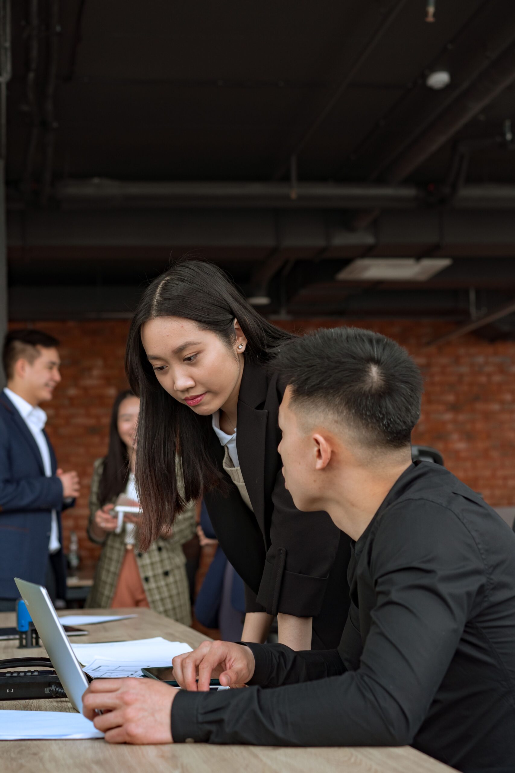 Consultant helping a colleague at a laptop